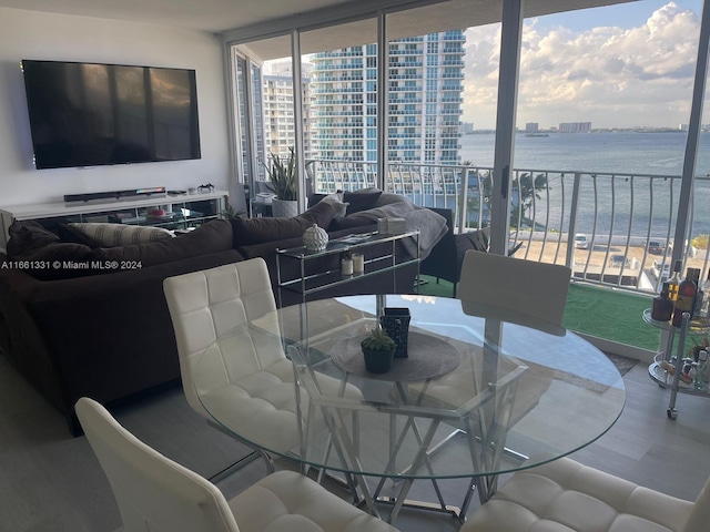 dining room featuring floor to ceiling windows, a water view, and hardwood / wood-style floors