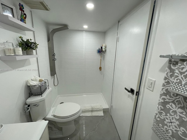 bathroom with a tile shower and toilet