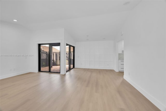 spare room featuring light wood-type flooring and lofted ceiling