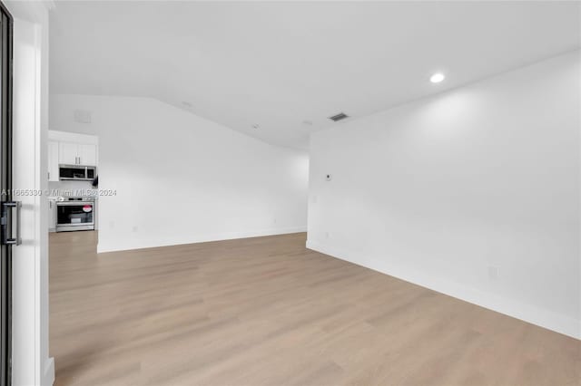 unfurnished room with vaulted ceiling and light hardwood / wood-style flooring