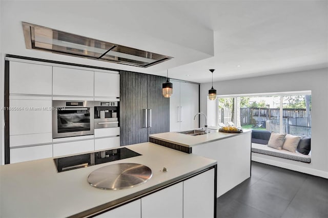 kitchen featuring white cabinets, oven, decorative light fixtures, and sink