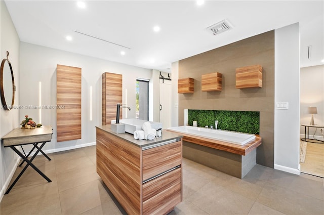 interior space with light tile patterned floors, sink, a barn door, and a kitchen island