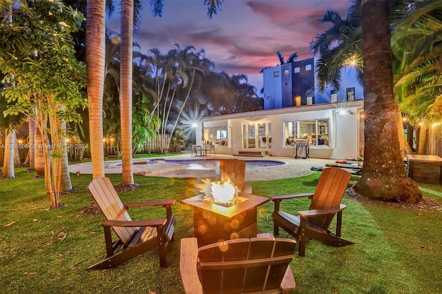 back house at dusk featuring a yard and a patio area