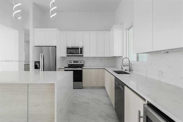 kitchen featuring light stone countertops, white cabinetry, appliances with stainless steel finishes, and sink