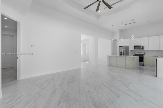 unfurnished living room with a towering ceiling and ceiling fan