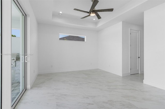 spare room featuring a tray ceiling and ceiling fan