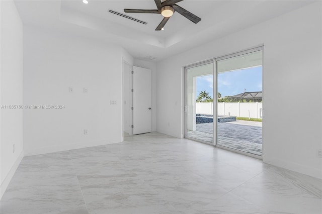 spare room featuring ceiling fan and a raised ceiling