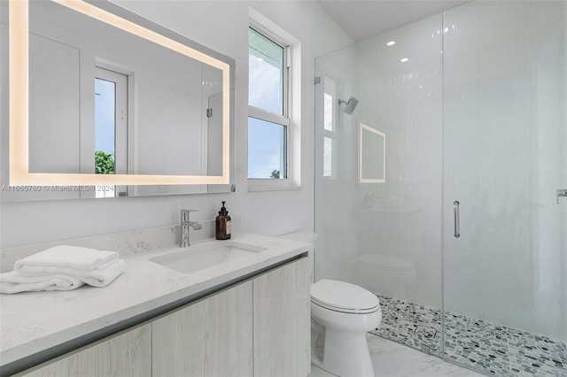 bathroom featuring a shower with shower door, vanity, and toilet