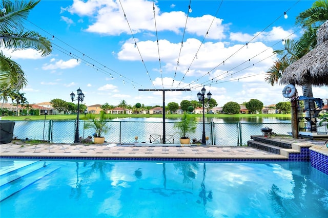 view of swimming pool featuring a patio area, an in ground hot tub, and a water view