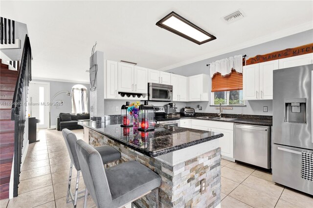 kitchen with sink, a breakfast bar area, ornamental molding, appliances with stainless steel finishes, and white cabinets