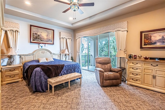 bedroom with ceiling fan, a tray ceiling, light colored carpet, and access to exterior