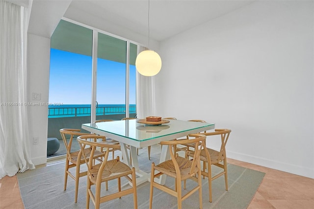 dining space featuring tile patterned flooring, a water view, and expansive windows