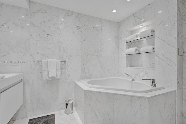 bathroom featuring tile walls, vanity, and a relaxing tiled tub