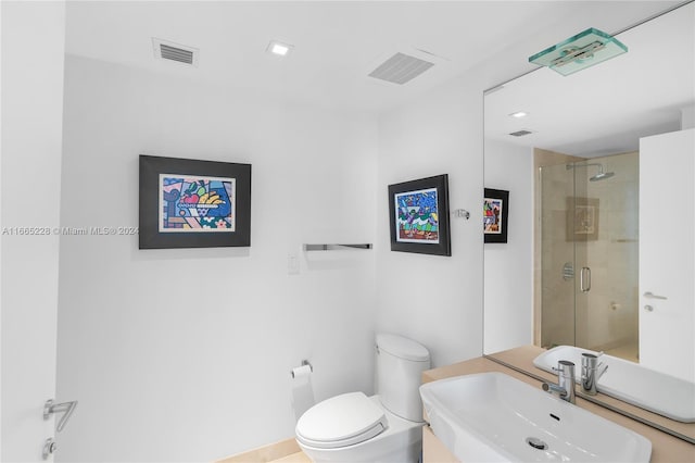 bathroom featuring sink, a shower with shower door, and toilet