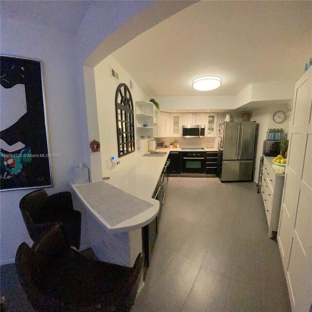 kitchen featuring stainless steel appliances, white cabinetry, and sink