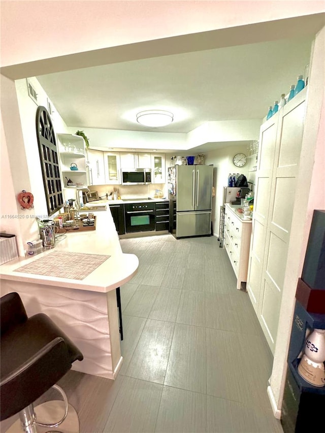 kitchen with sink, appliances with stainless steel finishes, a kitchen breakfast bar, white cabinets, and kitchen peninsula