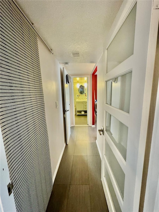 corridor featuring wood-type flooring and a textured ceiling