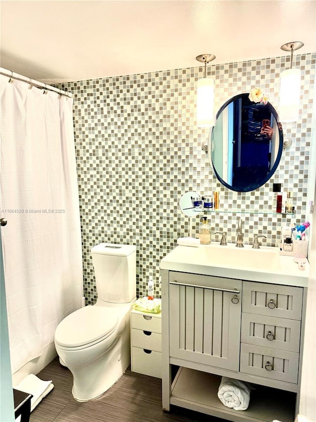 bathroom featuring vanity, toilet, wood-type flooring, and tile walls