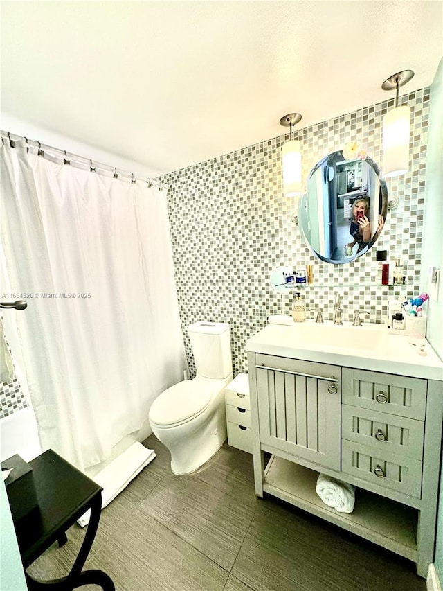 full bathroom with tile walls, vanity, decorative backsplash, toilet, and shower / bath combo with shower curtain