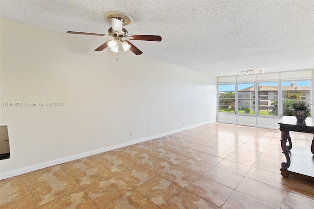 empty room with ceiling fan, light tile patterned floors, and a textured ceiling