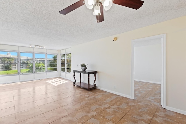 tiled spare room with rail lighting, ceiling fan, and a textured ceiling