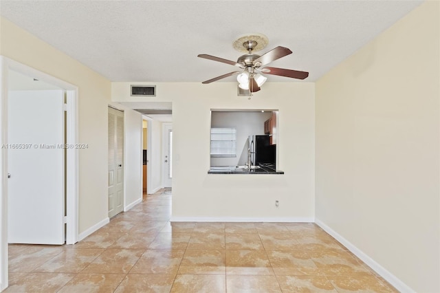 tiled empty room with a textured ceiling and ceiling fan