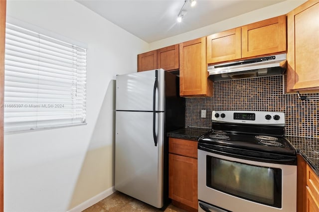 kitchen featuring appliances with stainless steel finishes, backsplash, dark stone counters, and light tile patterned floors