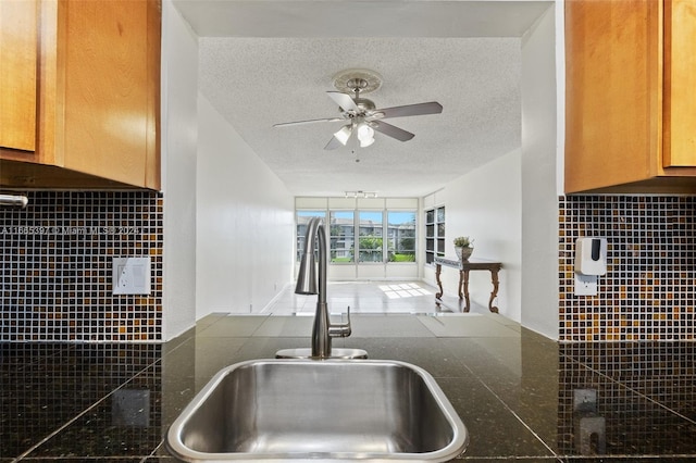 kitchen with a textured ceiling, tile walls, sink, and ceiling fan