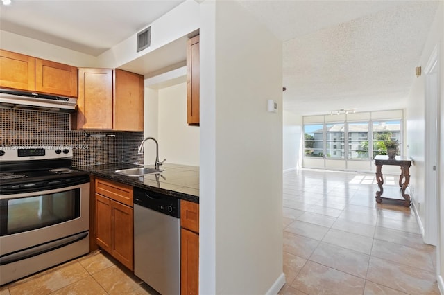 kitchen featuring light tile patterned floors, stainless steel appliances, a textured ceiling, and tasteful backsplash