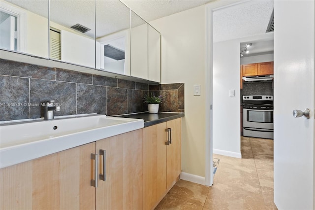 bathroom with a textured ceiling, backsplash, sink, and tile patterned floors