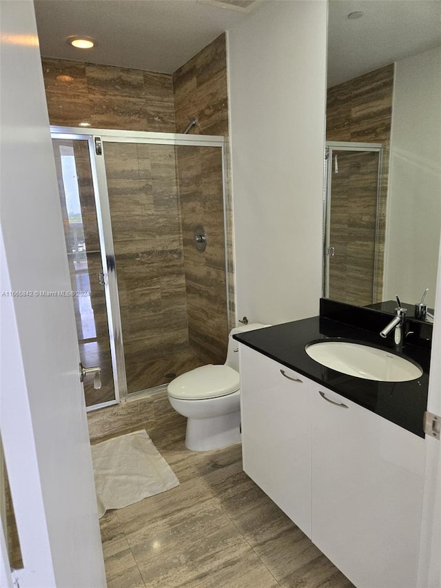 bathroom with vanity, toilet, and an enclosed shower