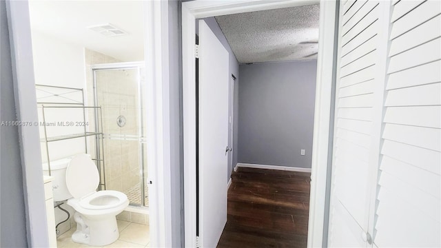 bathroom featuring walk in shower, a textured ceiling, toilet, and hardwood / wood-style flooring