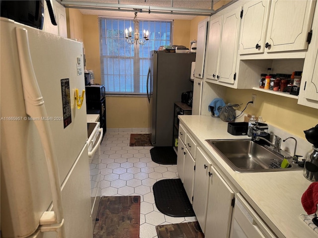 kitchen featuring white cabinets, sink, decorative light fixtures, an inviting chandelier, and white fridge