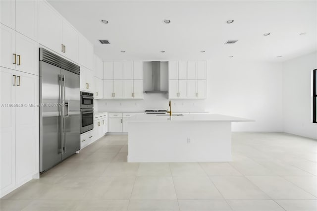 8095 Crystal Downs Ave, Boca Raton, FL 33434 - kitchen with stainless steel appliances, wall chimney range hood, light countertops, a center island with sink, and white cabinets