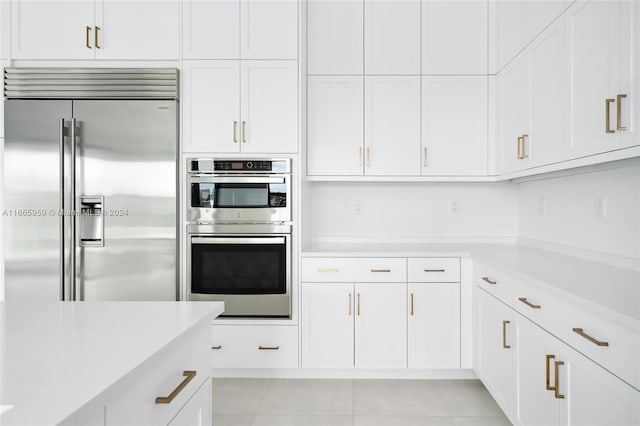 kitchen featuring light tile patterned flooring, white cabinetry, and stainless steel appliances