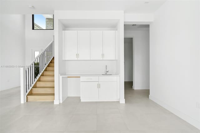 kitchen featuring light tile patterned flooring, sink, and white cabinets