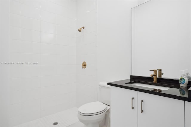 bathroom with vanity, toilet, and tiled shower