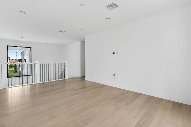 empty room featuring light wood-type flooring and an inviting chandelier