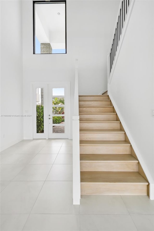 stairs with a high ceiling and tile patterned flooring