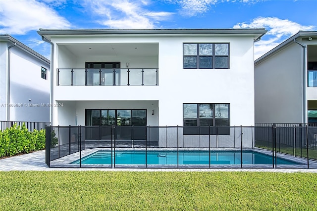 back of house with a balcony, a yard, a fenced in pool, and a patio area