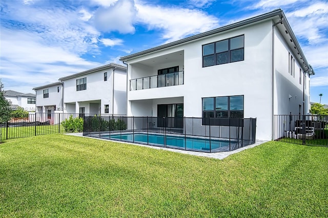 back of house featuring a lawn, a fenced in pool, and a balcony