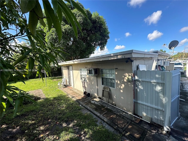 view of side of property featuring a yard and an AC wall unit