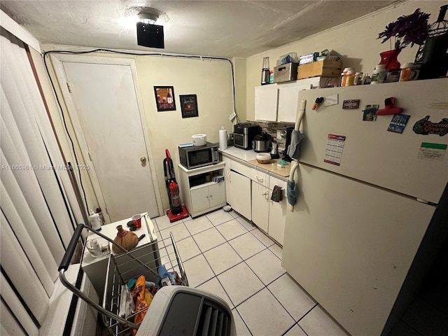 kitchen featuring white refrigerator, white cabinetry, and light tile patterned floors