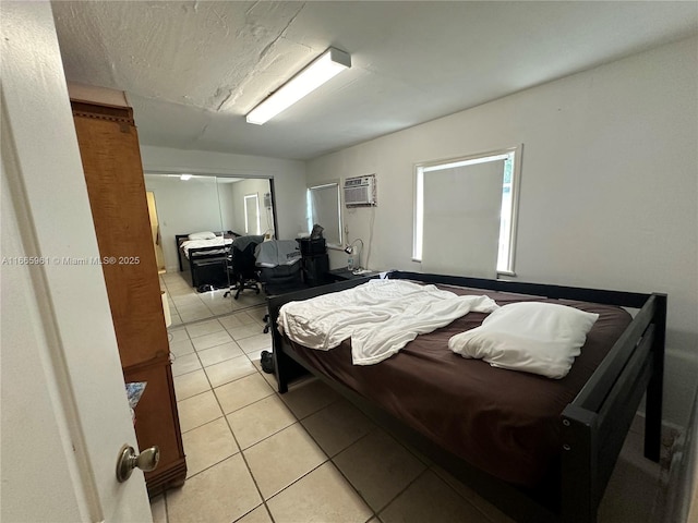 bedroom with a wall mounted AC, light tile patterned flooring, and a textured ceiling