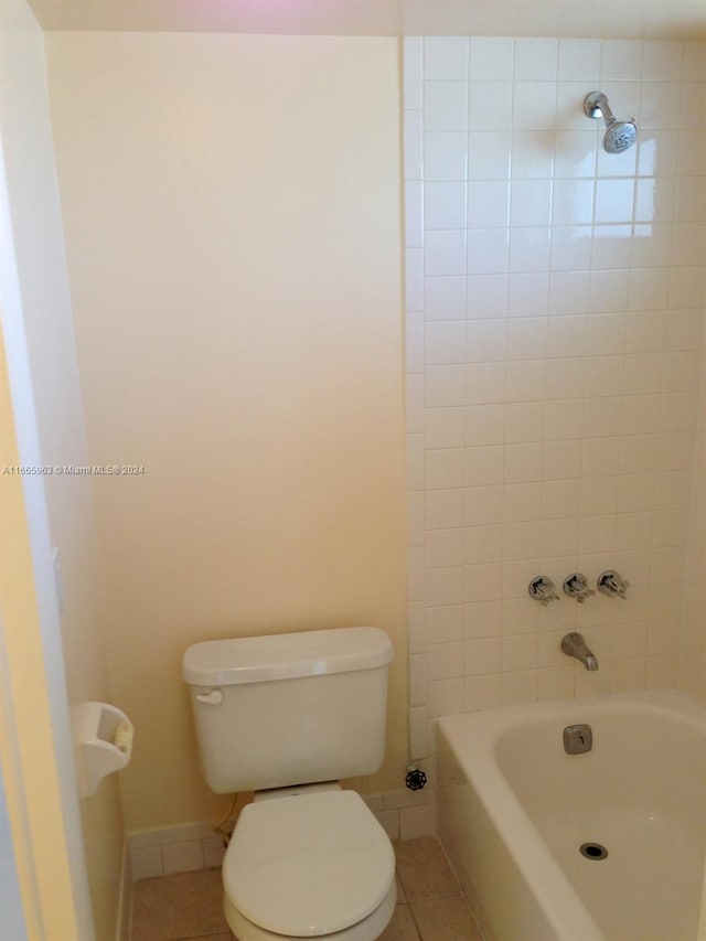 bathroom featuring tiled shower / bath combo, tile patterned floors, and toilet