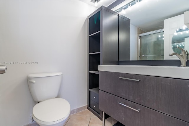 bathroom featuring tile patterned flooring, a shower with shower door, vanity, and toilet