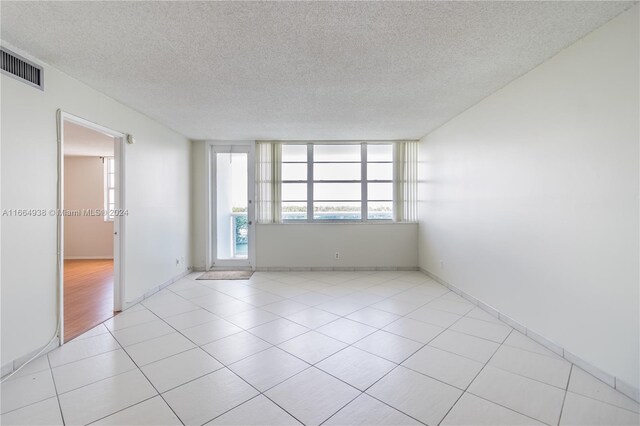 empty room with a textured ceiling and light tile patterned flooring