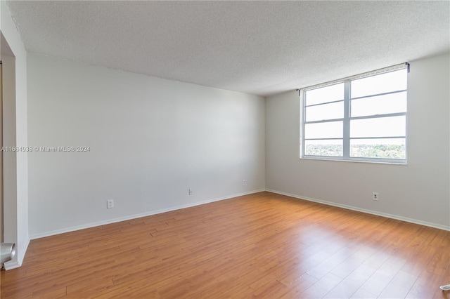 unfurnished room with a textured ceiling and light hardwood / wood-style floors