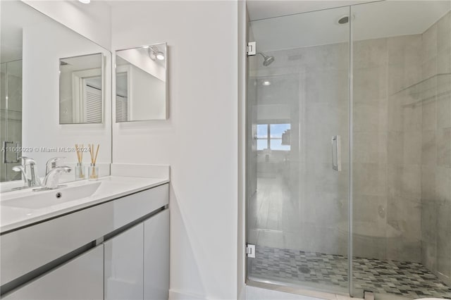 bathroom featuring a shower with shower door and vanity