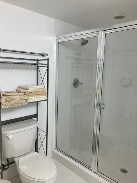 bathroom featuring tile patterned flooring, toilet, and an enclosed shower